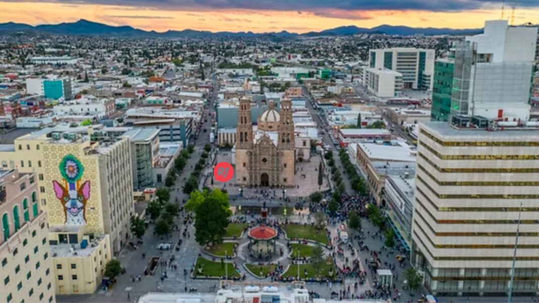 Vista urbana de una ciudad moderna con zonas comerciales y personas caminando, representando el debate sobre calidad de vida y costo urbano.